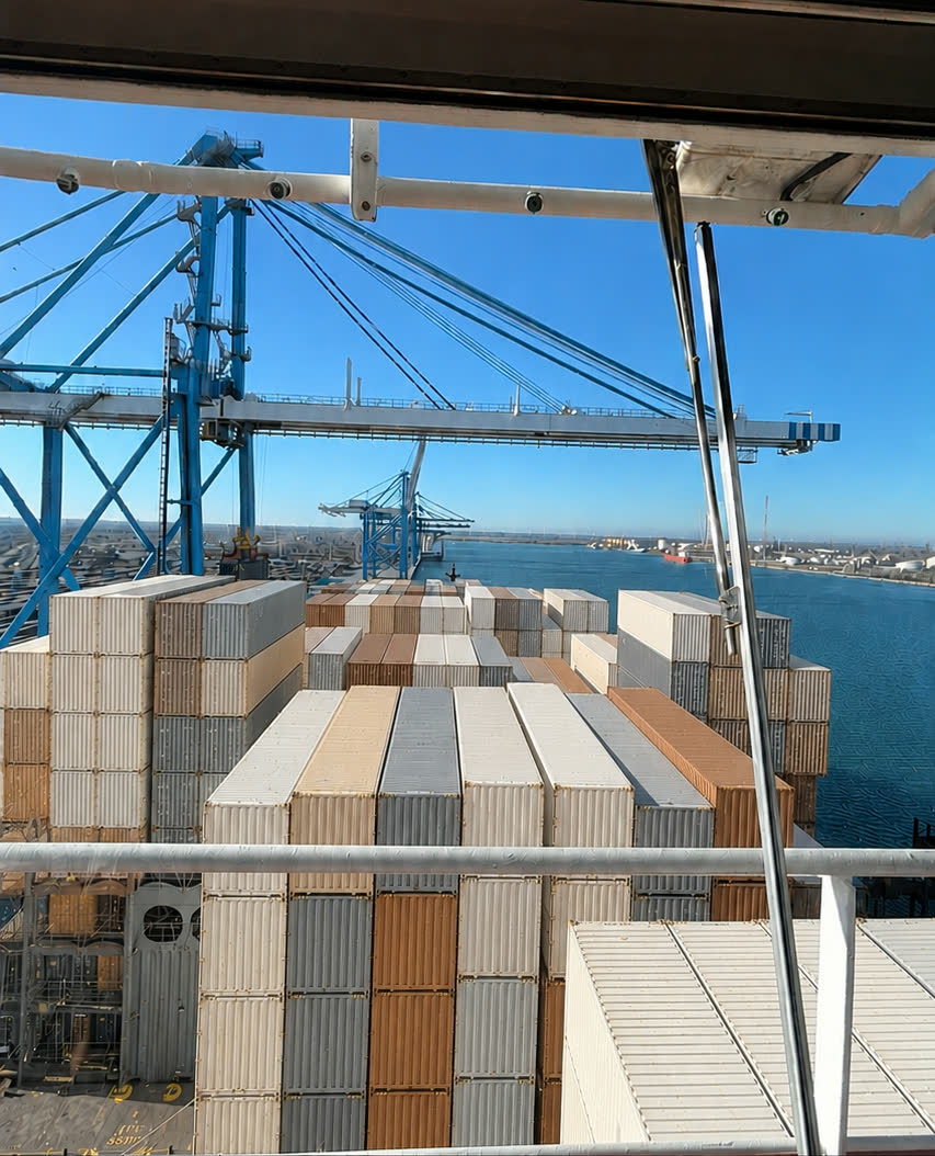 Pont d’un porte-conteneurs chargé, vu depuis la passerelle, portiques et bassin en arrière-plan