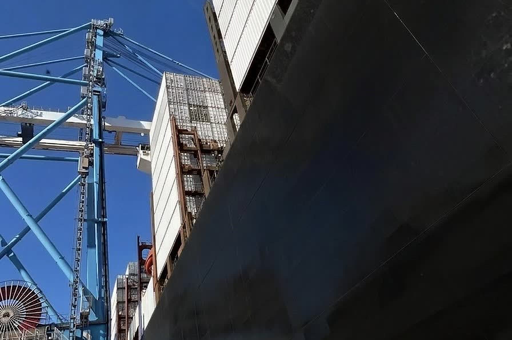 Porte-conteneurs à quai vu depuis le quai, portiques de manutention en arrière-plan